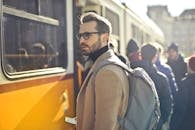 A stylish man with a backpack boards a tram in bustling Budapest, Hungary, during the day.